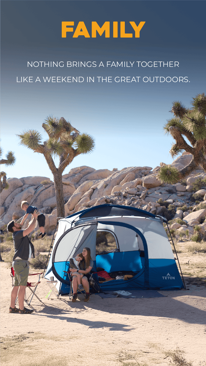 Family Solutions Family camping in a desert landscape with the Hacienda tent, surrounded by rocky terrain and Joshua trees.