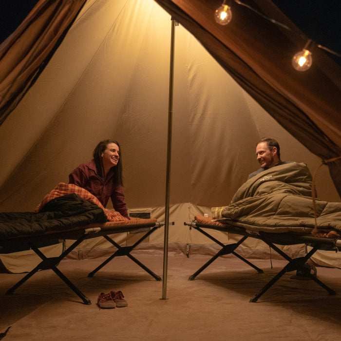 Two people sitting inside a tent with warm lighting