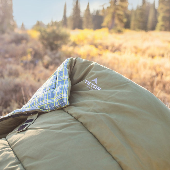 green Camping sleeping bag with Teton brand logo in a forest setting