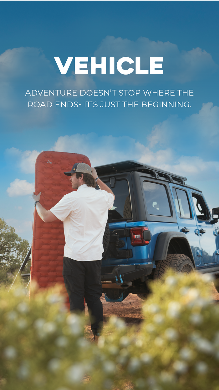 Vehicle Camping Solutions: Person standing next to a blue SUV with a red object, against a blue sky with clouds.