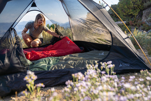 Woman places bags inside tent.