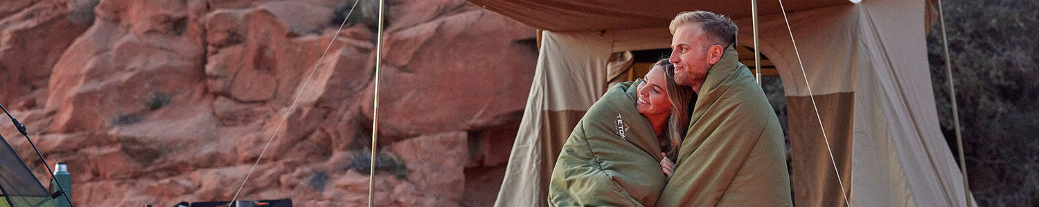 A man and a woman snuggle together in their TETON Sports Mammoth Evergreen sleeping bag.