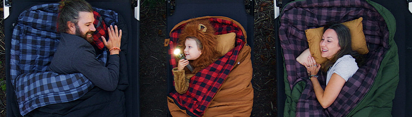 A family shown from above snuggled into their new TETON Sports Bridger Canvas Sleeping Bags in multiple colors and sizes.