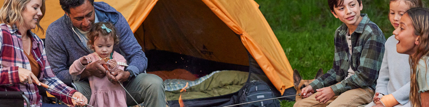 A family camps together, making s'mores beside an open TETON Sports tent.