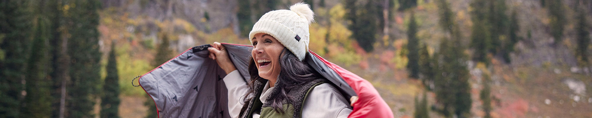 A woman outdoors with her Acadia camp blanket