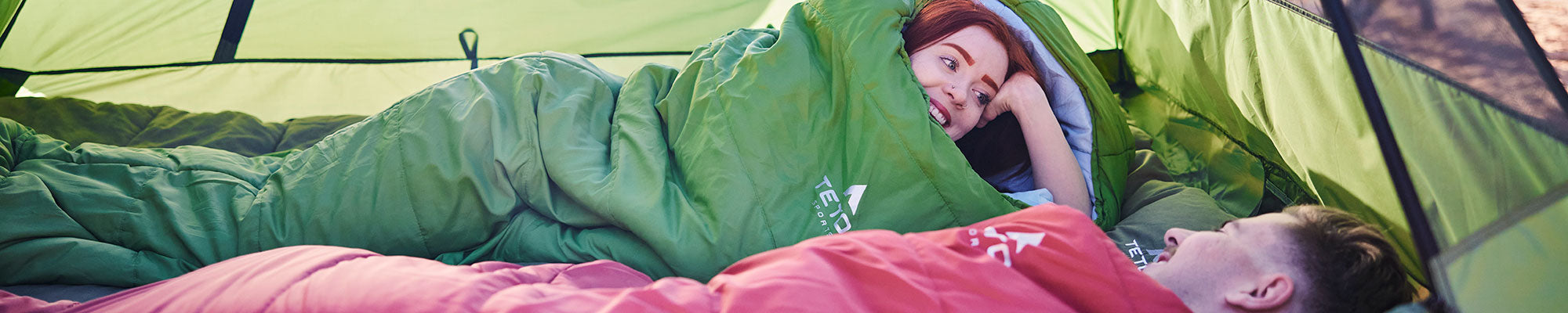 A man and a woman snuggled in their TETON Sports sleeping bags.