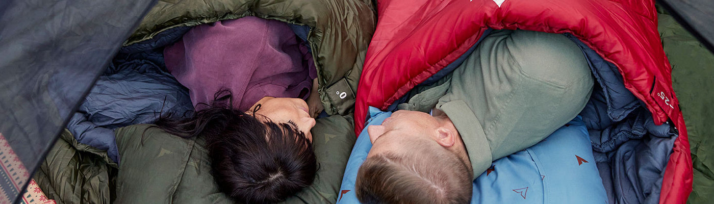 A man and a woman lying in sleeping bags with their new TETON Sports Grand Pillows.