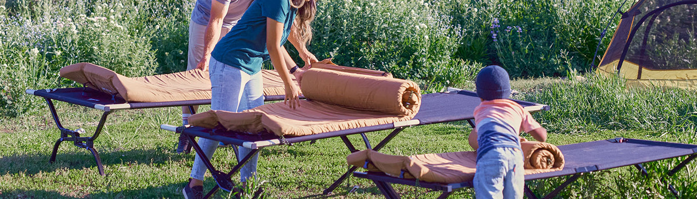 Two parents and a child roll out their TETON Sports canvas camp pads.