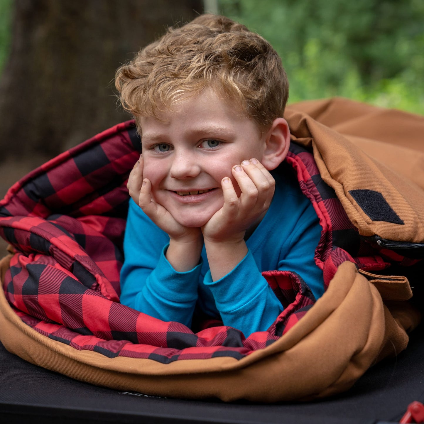 Child in a bridger sleeping bag with red and black checkers