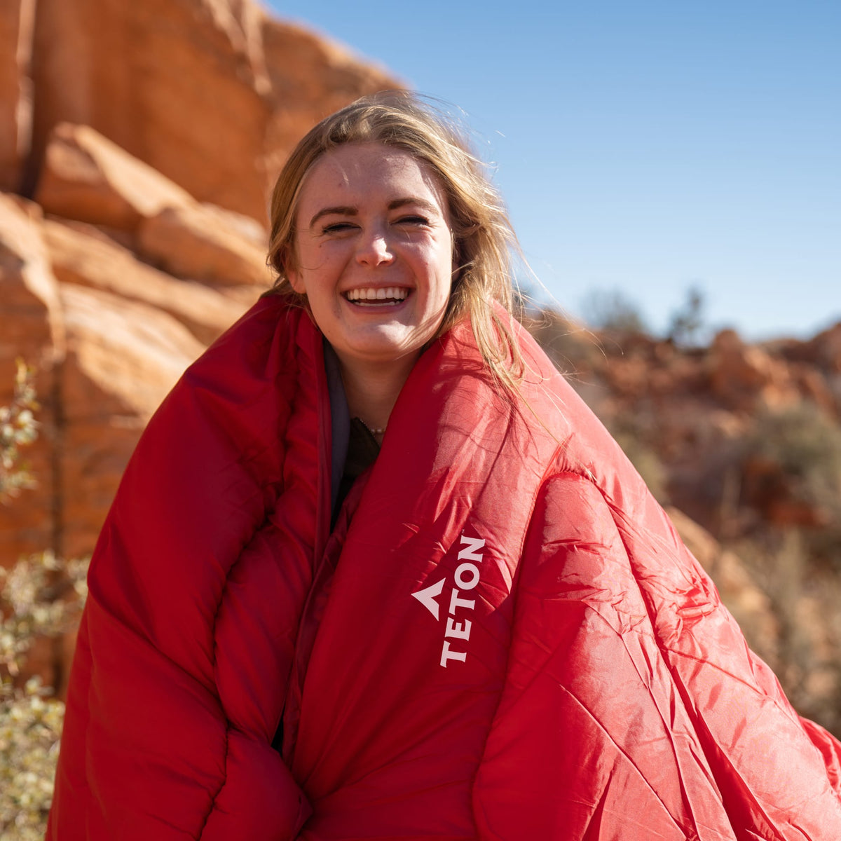 Person wearing a Celsius Ruby sleeping bag in a desert setting
