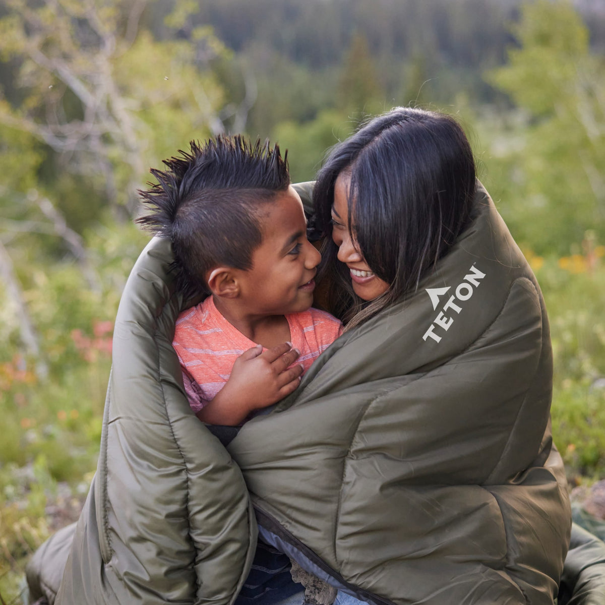 Mother & son wrapped in a Celsius sleeping bag in a forest setting