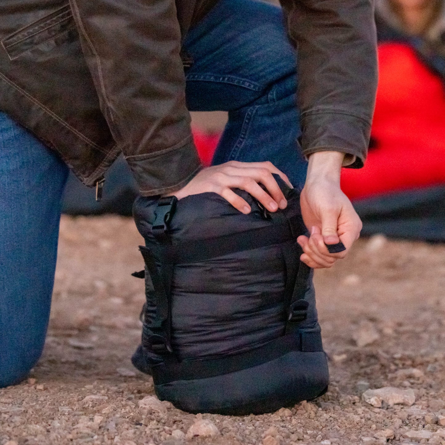 Person stuffing a sleeping bag in a stuff sack