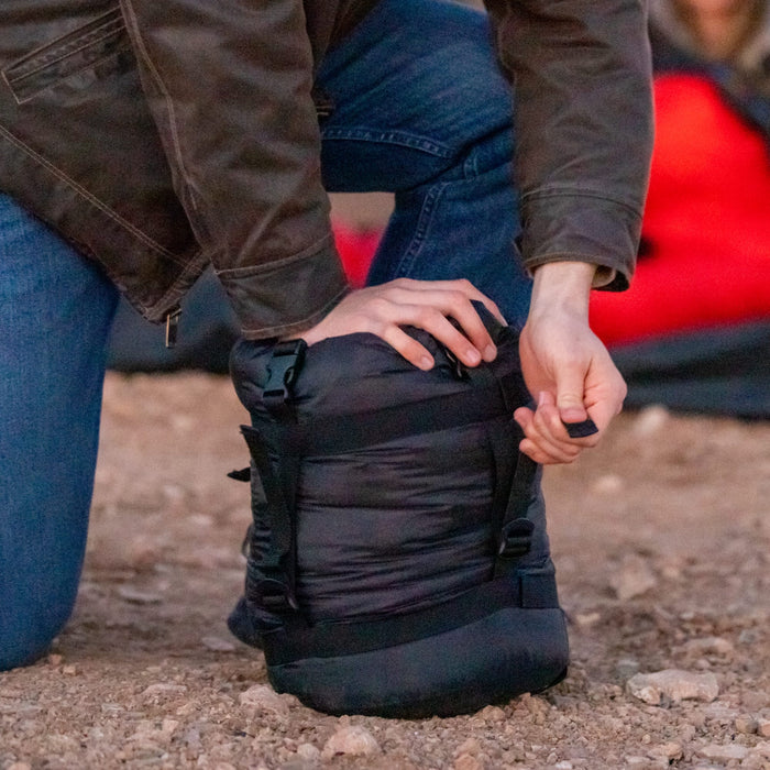 Person stuffing a sleeping bag in a stuff sack