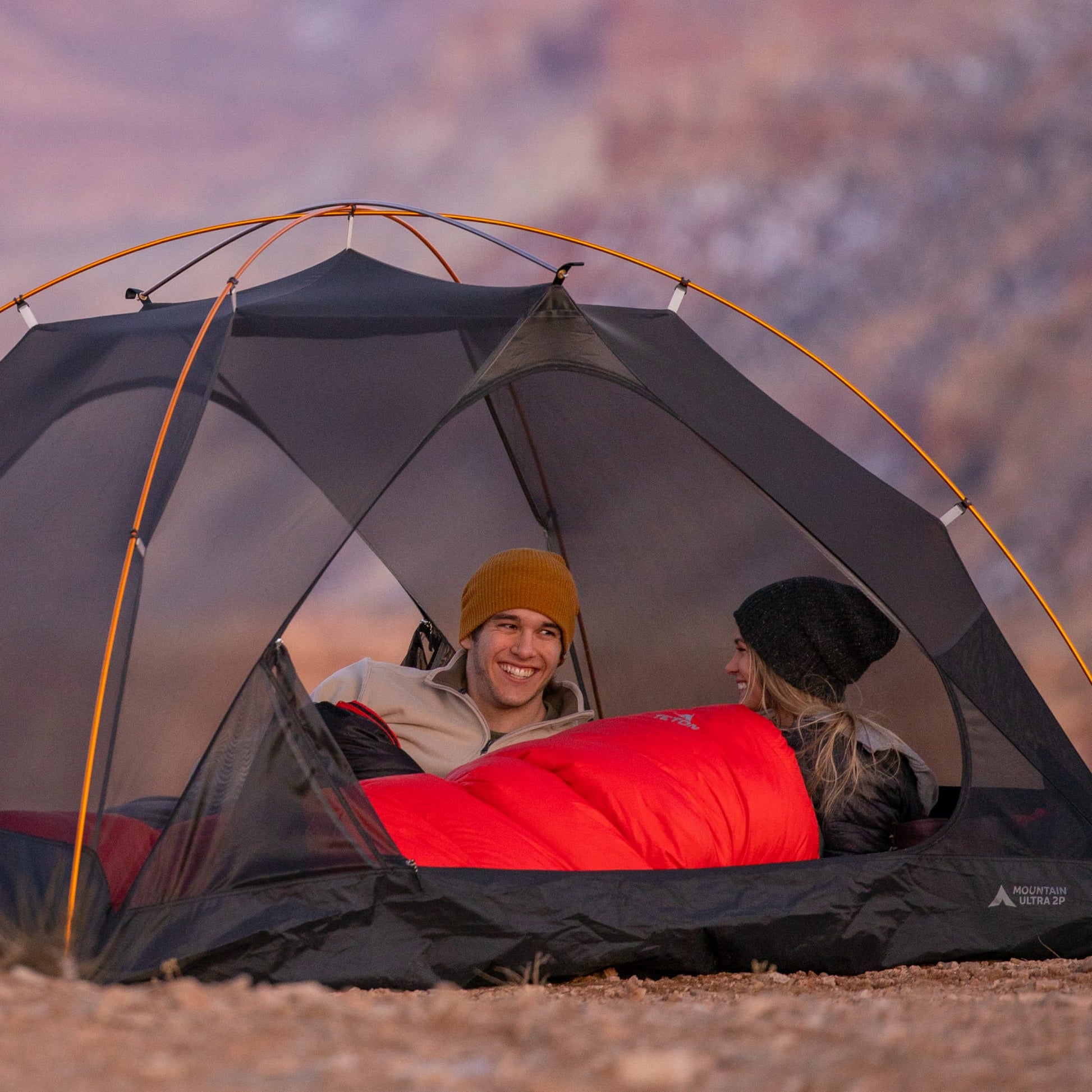 Two people inside a camping tent with a scenic background