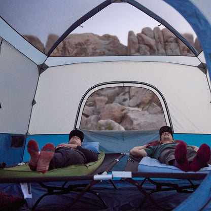 2 men lying on a camp cot to show off the vertical wall set-up of the tent.