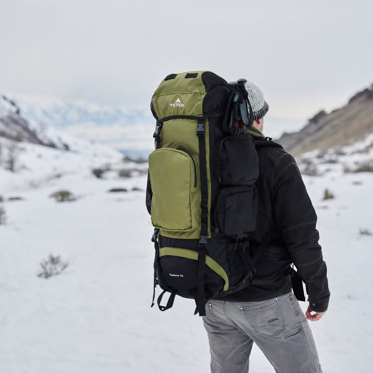 Person wearing a large 75L green and black backpack in a snowy landscape