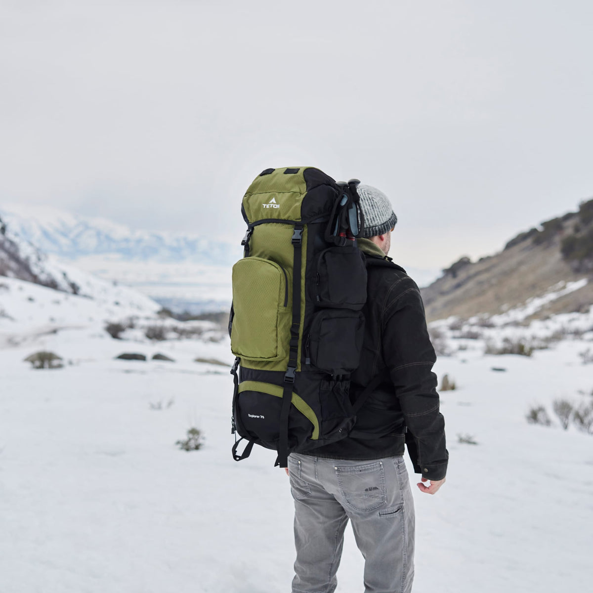 Person with a large 75L green backpack in a snowy landscape