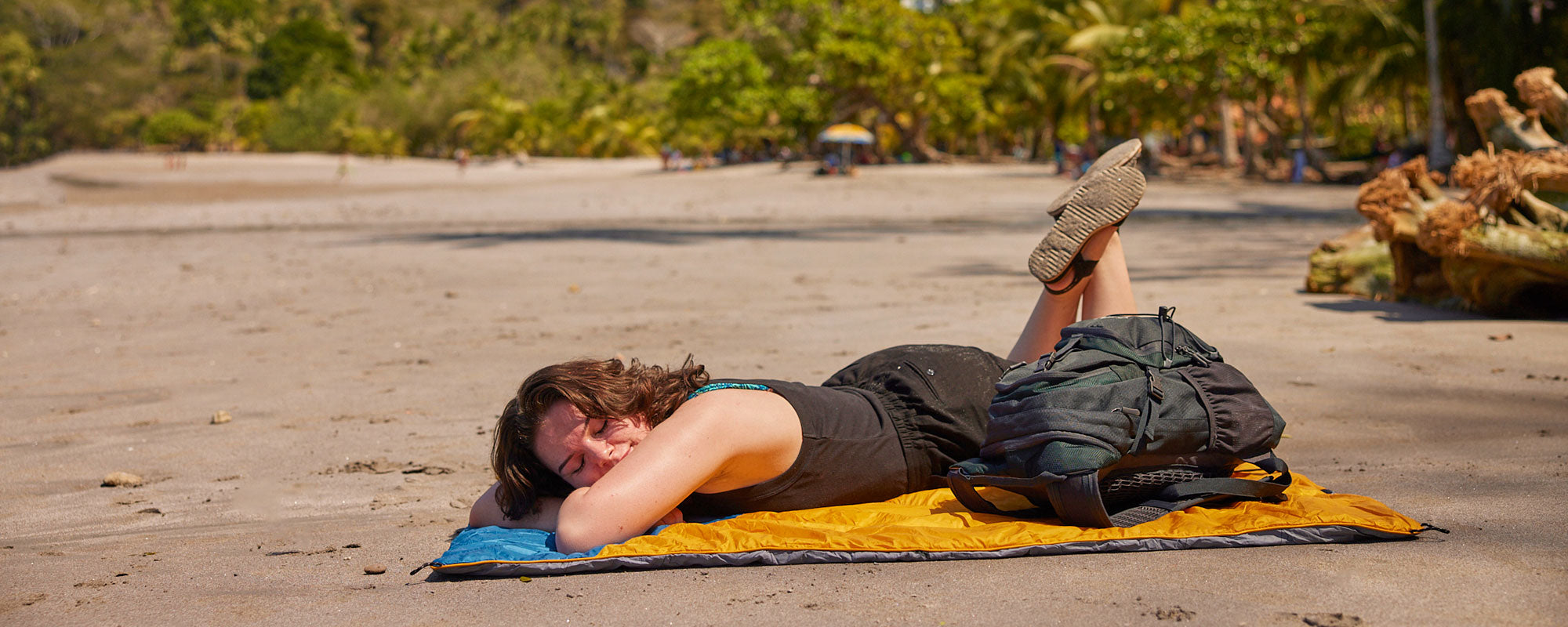 A woman sleeping on her Teton blanket on the beach
