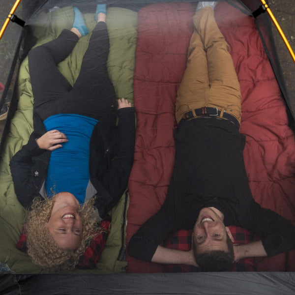2 people lying inside the mountain ultra tent with the mesh exposed for airflow and stargazing.