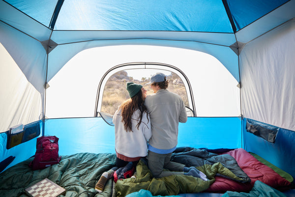 A couple in front of a large mesh window on a tent