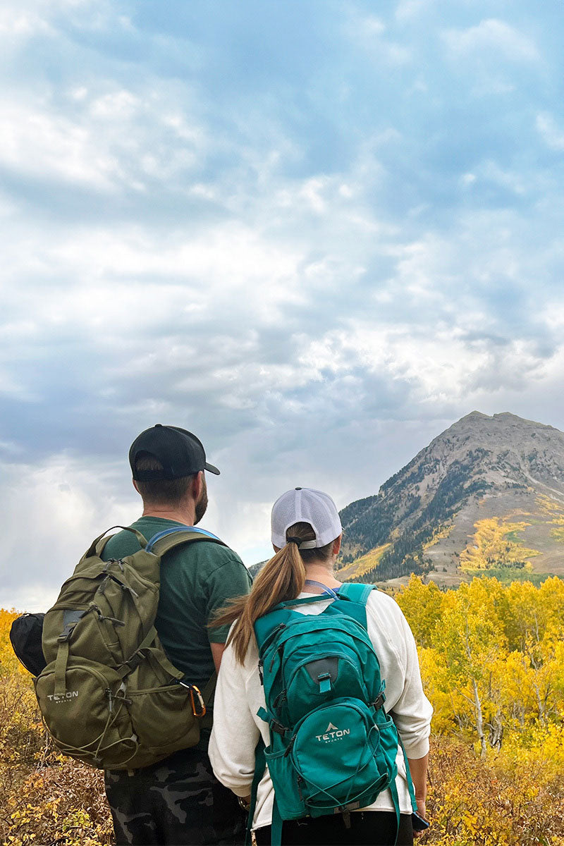 A man and a woman on a fall hike with their Oasis hydration packs