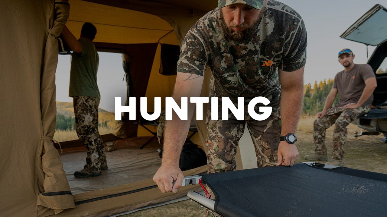 Man in camouflage setting up a camping cot with 'Hunting' text overlay.