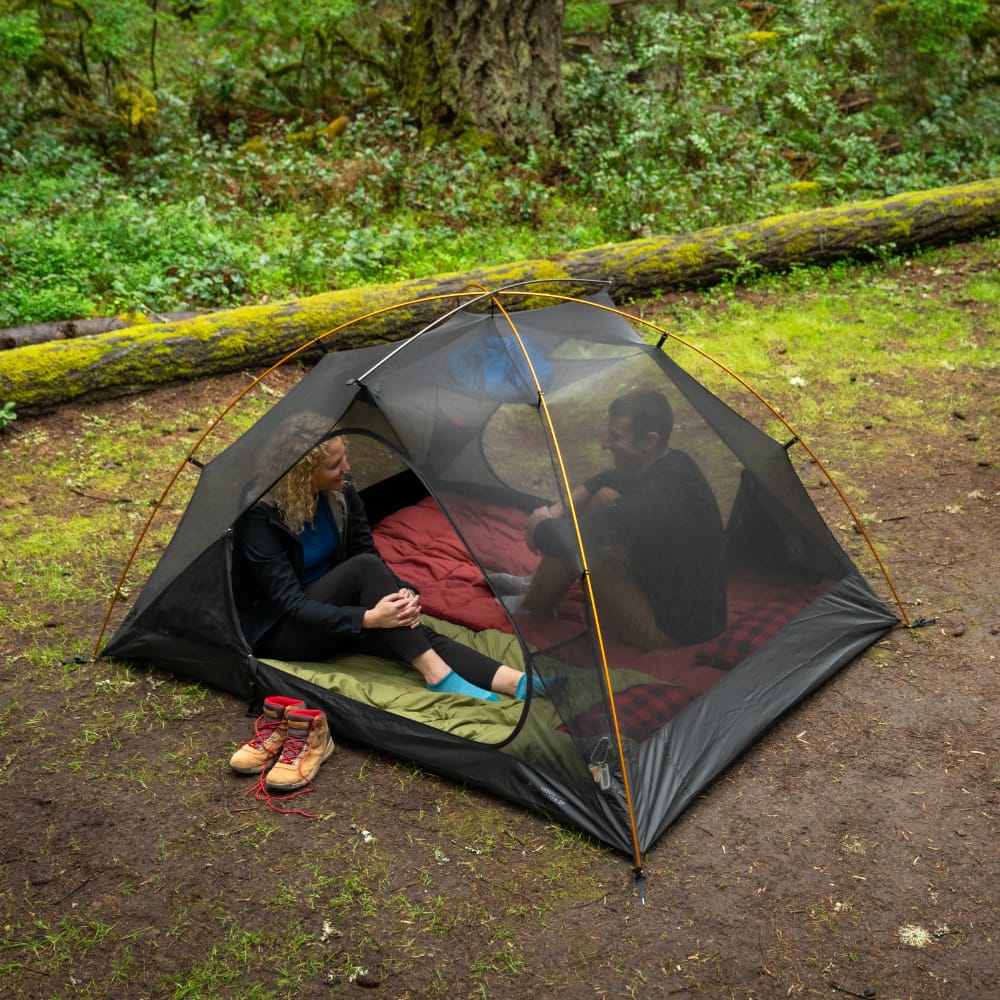 Two people inside the mesh of Mountain Ultra 2-person tent in a forest setting without the cover.
