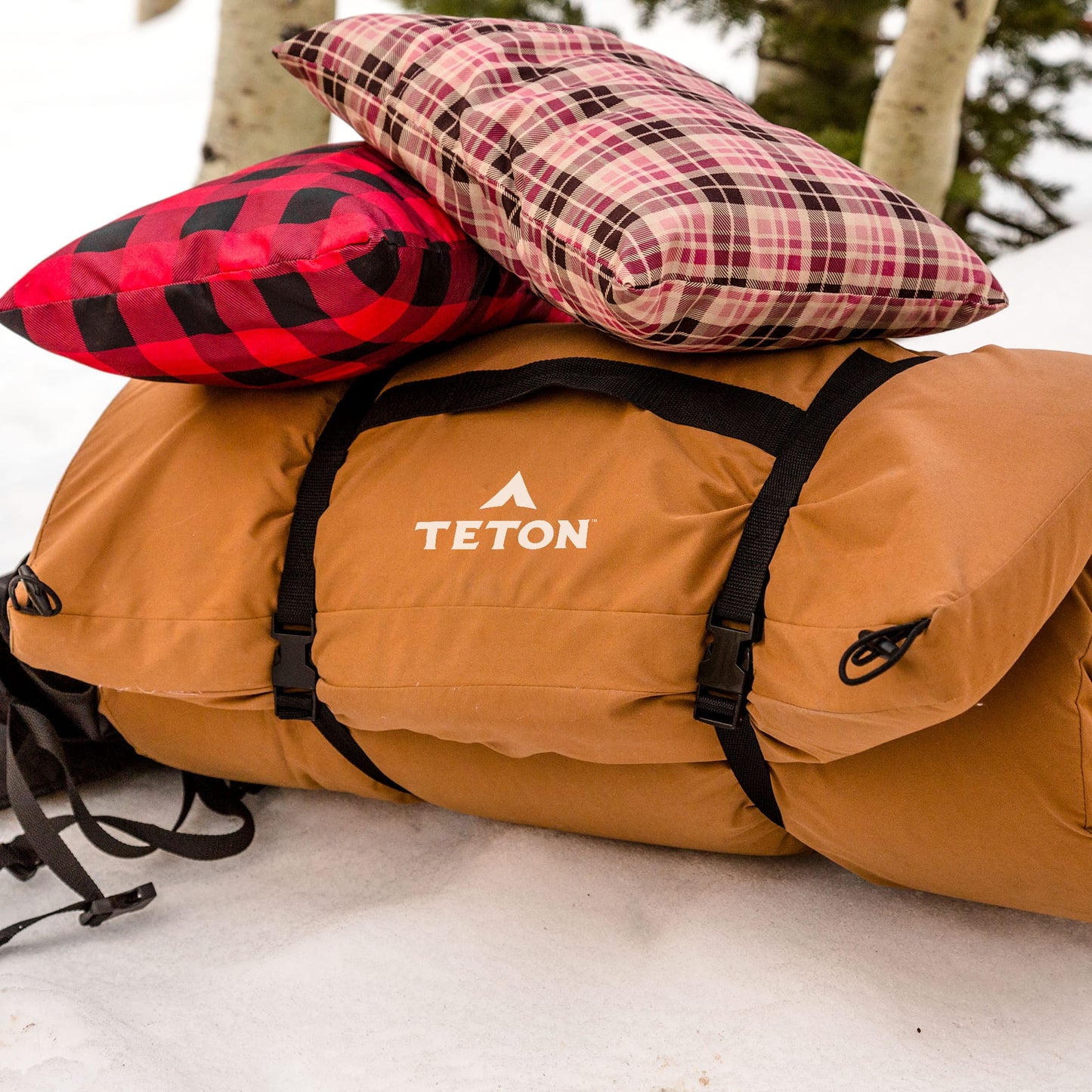 Brown Teton Canvas Camping Pad with plaid pillows on a snowy ground