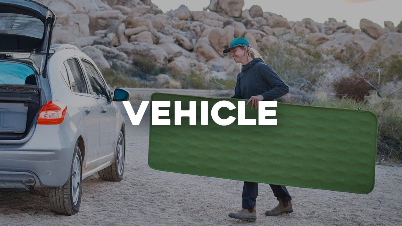 Person holding the sequoia sleeping pad next to a car in a desert setting with "Vehicle" text overlay.