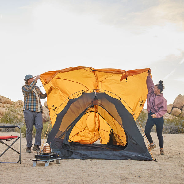 2 people covering the tent with the rainfly. 2 zipper doors are visible.